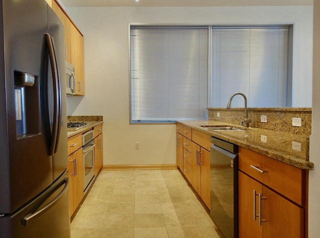 kitchen with light stone counters, light tile patterned floors, sink, and appliances with stainless steel finishes