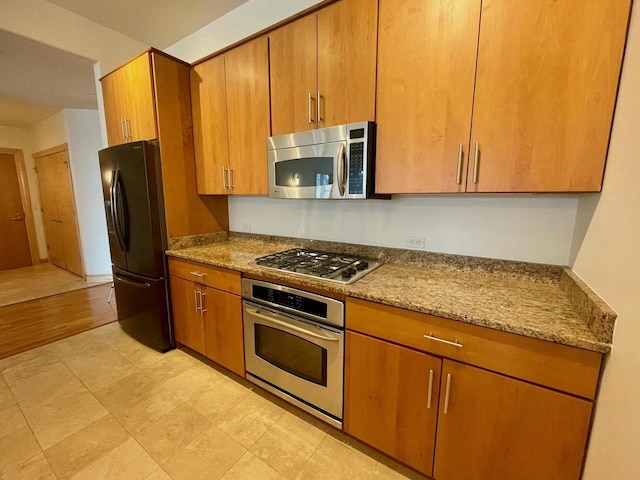 kitchen with light hardwood / wood-style floors, light stone countertops, and appliances with stainless steel finishes