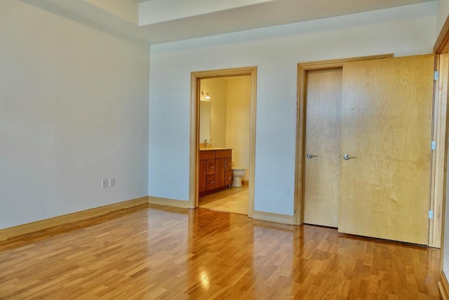 unfurnished bedroom with light hardwood / wood-style floors and ensuite bath