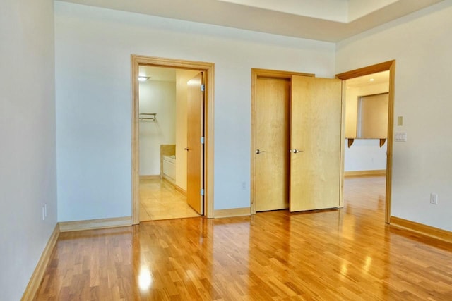 unfurnished bedroom featuring hardwood / wood-style floors and ensuite bath