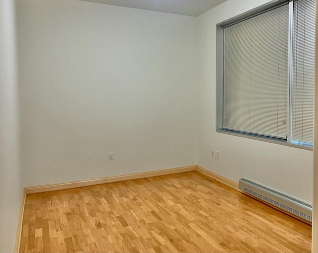 empty room featuring light wood-type flooring and a baseboard heating unit