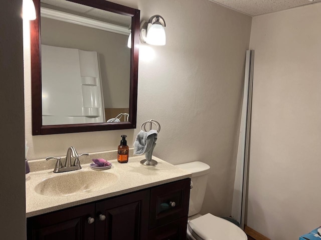 bathroom with vanity, toilet, and a textured ceiling