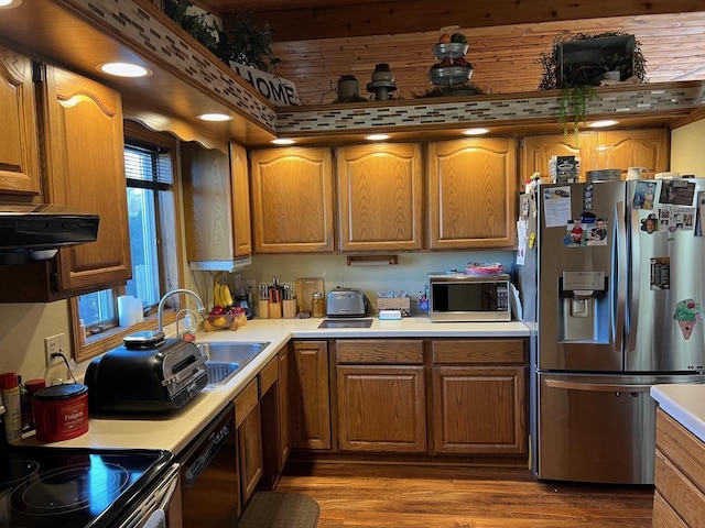 kitchen with exhaust hood, sink, stainless steel appliances, and hardwood / wood-style flooring