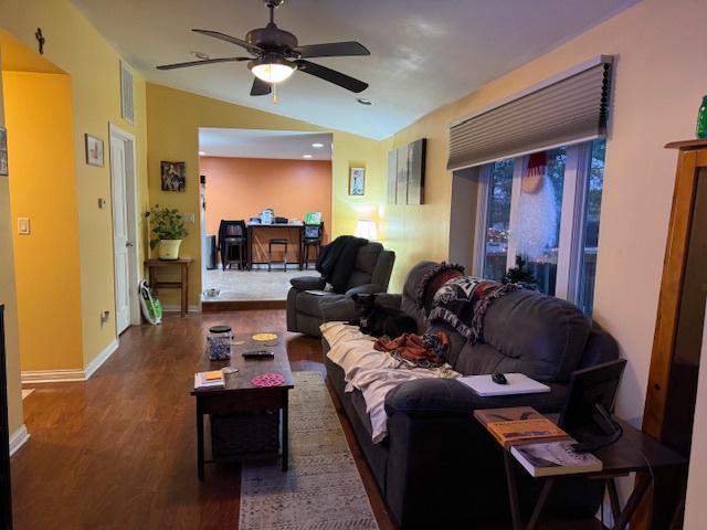 living room featuring vaulted ceiling, dark hardwood / wood-style floors, and ceiling fan