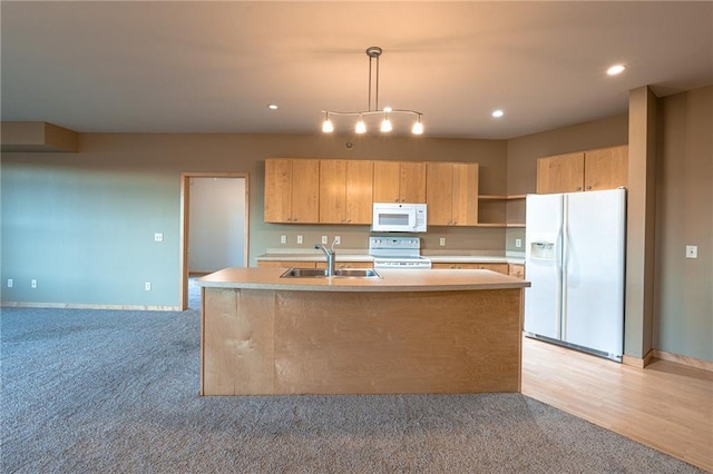 kitchen with decorative light fixtures, white appliances, sink, and an island with sink