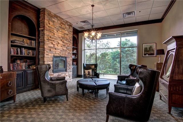 living area featuring a chandelier, carpet floors, a stone fireplace, and built in features