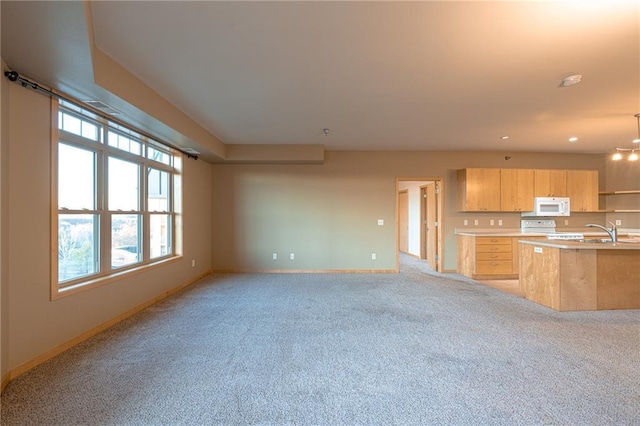 unfurnished living room featuring light carpet, a wealth of natural light, and sink