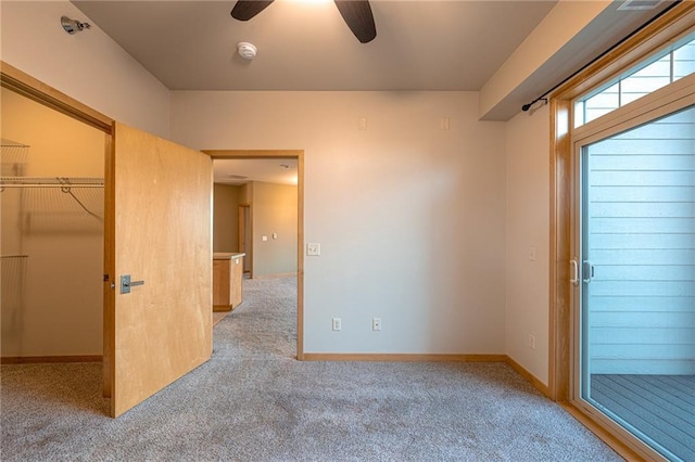 unfurnished bedroom with light colored carpet, a spacious closet, a closet, and ceiling fan