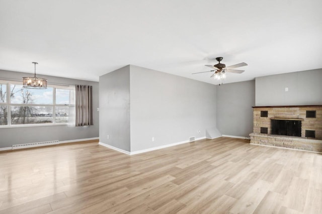 unfurnished living room with ceiling fan with notable chandelier and light hardwood / wood-style floors