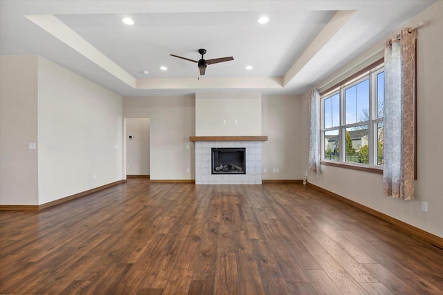 5550 N Amethyst Dr, Appleton, WI 54913 - unfurnished living room with a tile fireplace, dark hardwood / wood-style flooring, a raised ceiling, and ceiling fan