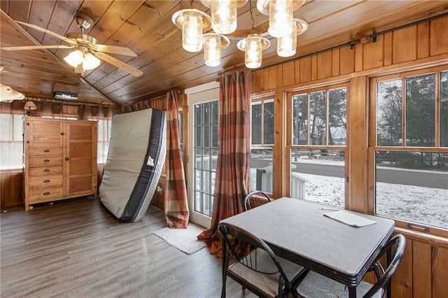 dining area featuring ceiling fan with notable chandelier, wooden walls, wooden ceiling, hardwood / wood-style floors, and lofted ceiling