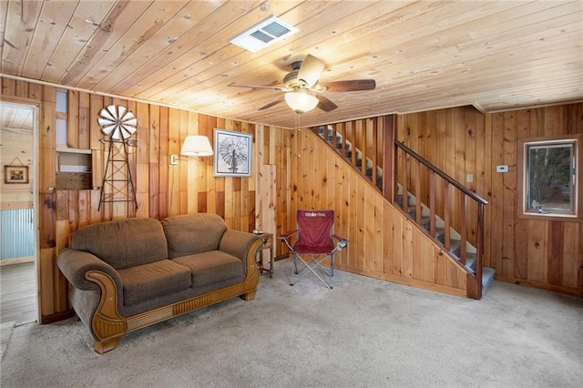 carpeted living room with wooden ceiling, ceiling fan, and wooden walls