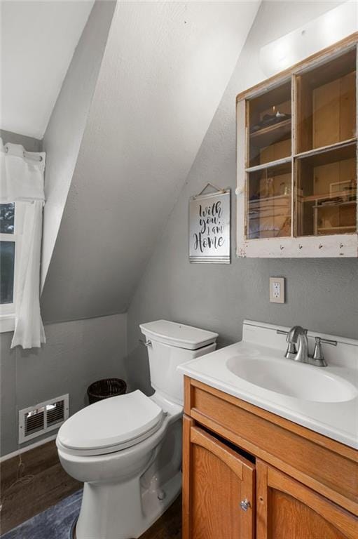 bathroom with vanity, toilet, wood-type flooring, and lofted ceiling