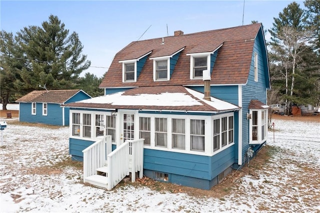 snow covered house featuring a sunroom