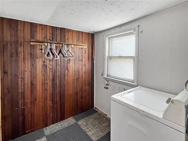 clothes washing area with washer and clothes dryer, wood walls, and a textured ceiling