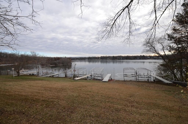 view of dock featuring a lawn and a water view