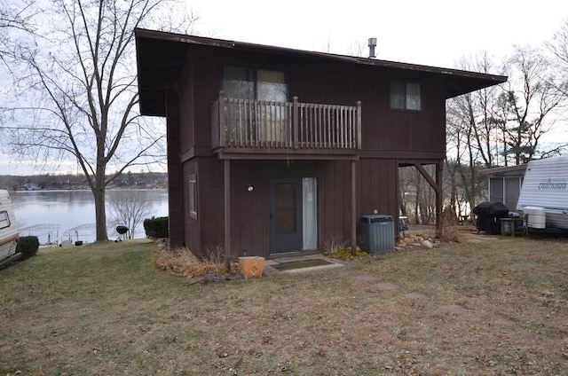 back of house with central air condition unit, a balcony, a water view, and a yard