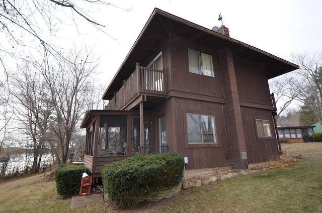 view of side of property with a yard and a balcony