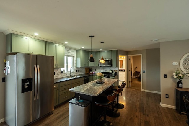 kitchen with dark stone counters, hanging light fixtures, dark hardwood / wood-style floors, appliances with stainless steel finishes, and a kitchen island