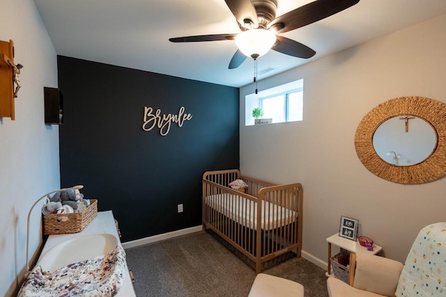 carpeted bedroom with ceiling fan and a crib