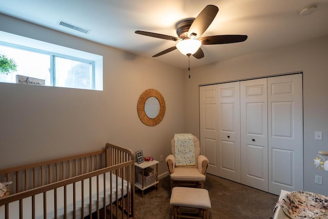 bedroom featuring a closet, dark carpet, a nursery area, and ceiling fan