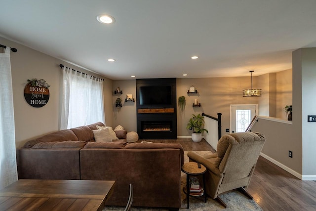 living room with dark hardwood / wood-style flooring, a large fireplace, and a wealth of natural light