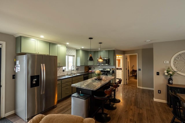 kitchen with dark hardwood / wood-style flooring, dark stone countertops, decorative light fixtures, a kitchen island, and appliances with stainless steel finishes