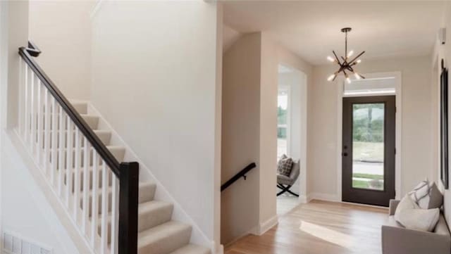 entryway featuring visible vents, baseboards, wood finished floors, stairs, and a notable chandelier