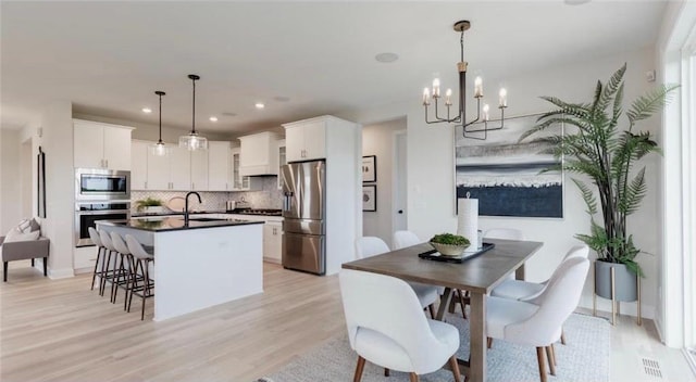 kitchen featuring tasteful backsplash, dark countertops, appliances with stainless steel finishes, white cabinetry, and an island with sink