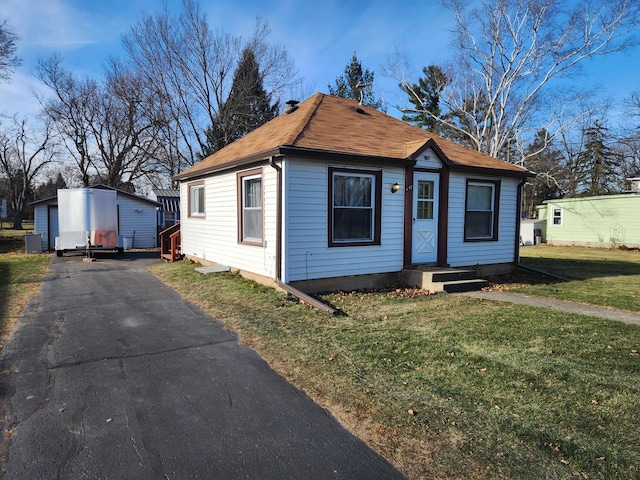 bungalow with a front lawn and an outdoor structure