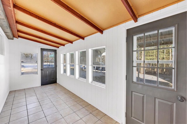 entryway featuring wood walls, light tile patterned floors, and lofted ceiling with beams