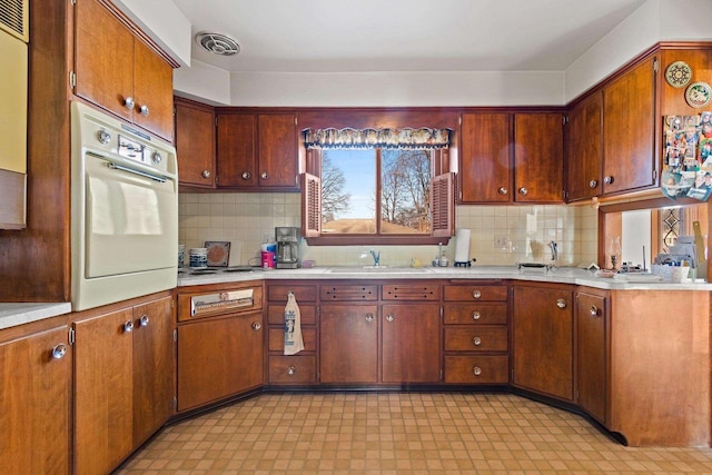 kitchen with white oven, backsplash, sink, and stainless steel gas cooktop