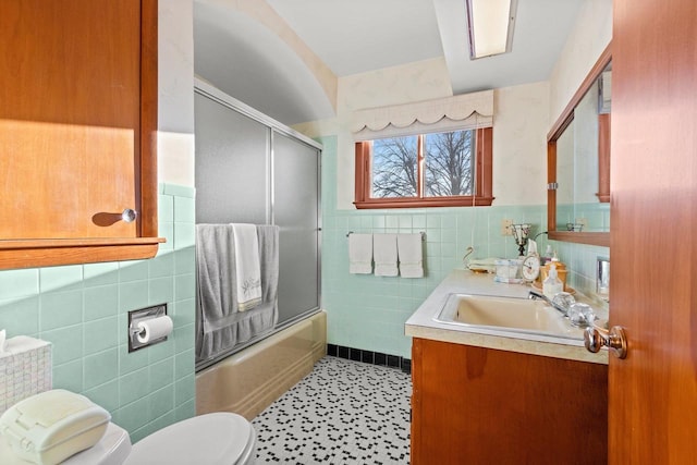 full bathroom with vanity, toilet, enclosed tub / shower combo, and tile walls