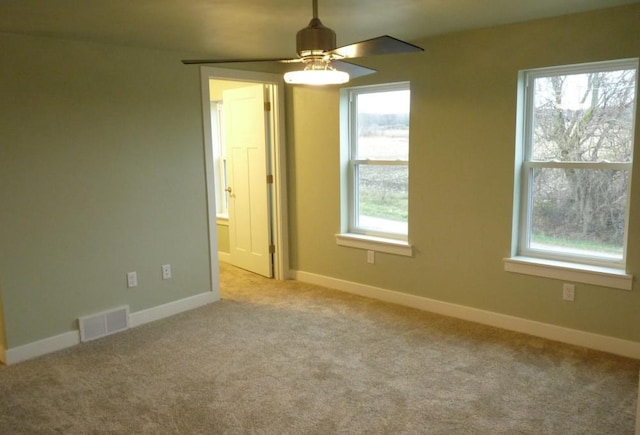 carpeted empty room with ceiling fan and a wealth of natural light