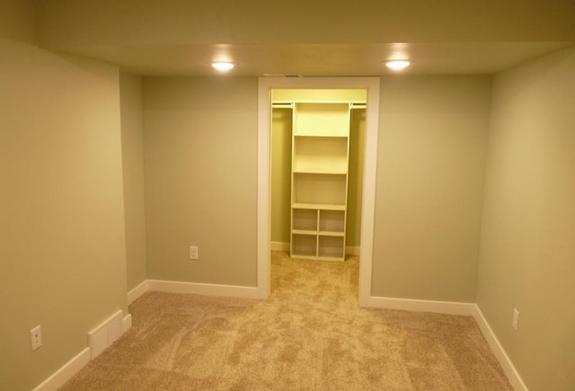 interior space with light colored carpet, a walk in closet, and a closet