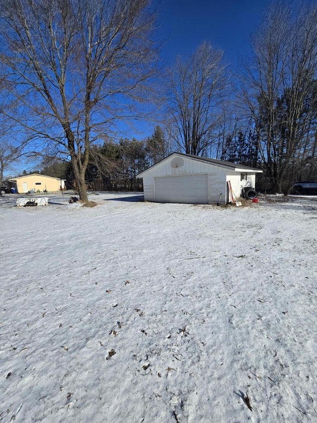 snowy yard with a garage and an outdoor structure