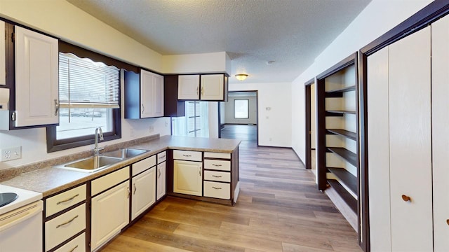 kitchen with white range, sink, light wood-type flooring, a textured ceiling, and kitchen peninsula