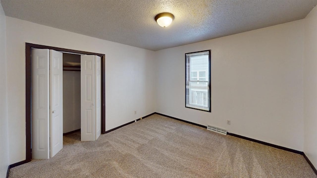 unfurnished bedroom featuring a textured ceiling, light colored carpet, and a closet