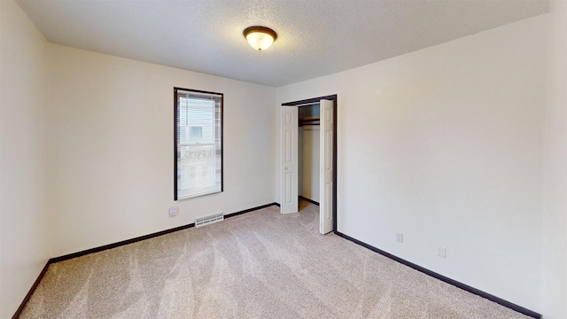 unfurnished room featuring light carpet and a textured ceiling