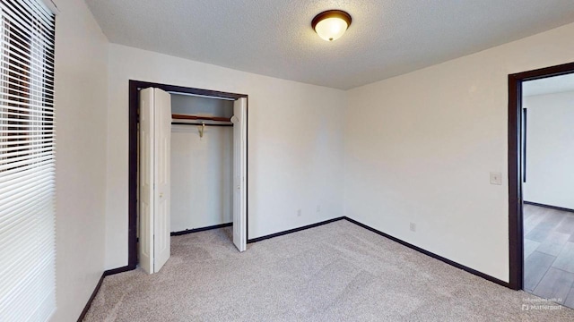 unfurnished bedroom featuring a closet, light colored carpet, and a textured ceiling