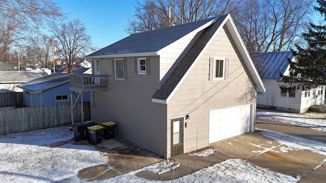 view of snowy exterior with a garage and a balcony