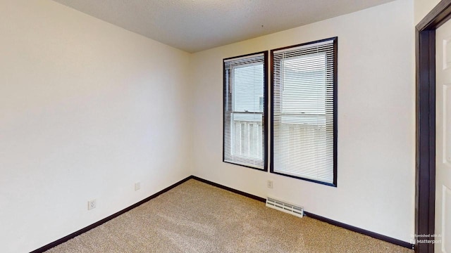 carpeted empty room with a textured ceiling