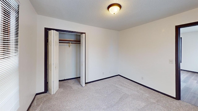 unfurnished bedroom with a textured ceiling, light colored carpet, and a closet