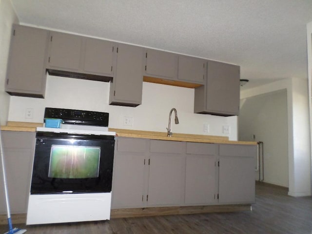 kitchen with wooden counters, white range oven, gray cabinets, and dark wood-type flooring