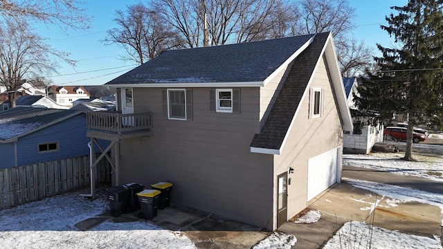 view of snow covered exterior featuring a balcony and a garage