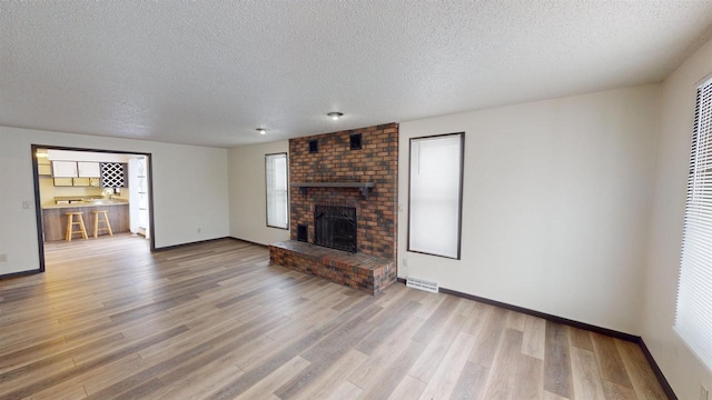 unfurnished living room with a fireplace, hardwood / wood-style floors, and a textured ceiling