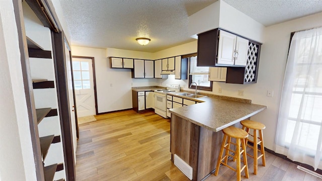 kitchen with white range with electric cooktop, light hardwood / wood-style floors, sink, and a wealth of natural light