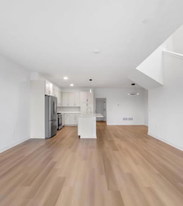 unfurnished living room featuring sink and light hardwood / wood-style flooring