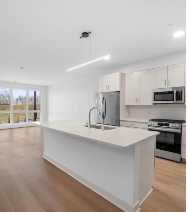 kitchen featuring white cabinetry, pendant lighting, an island with sink, and appliances with stainless steel finishes