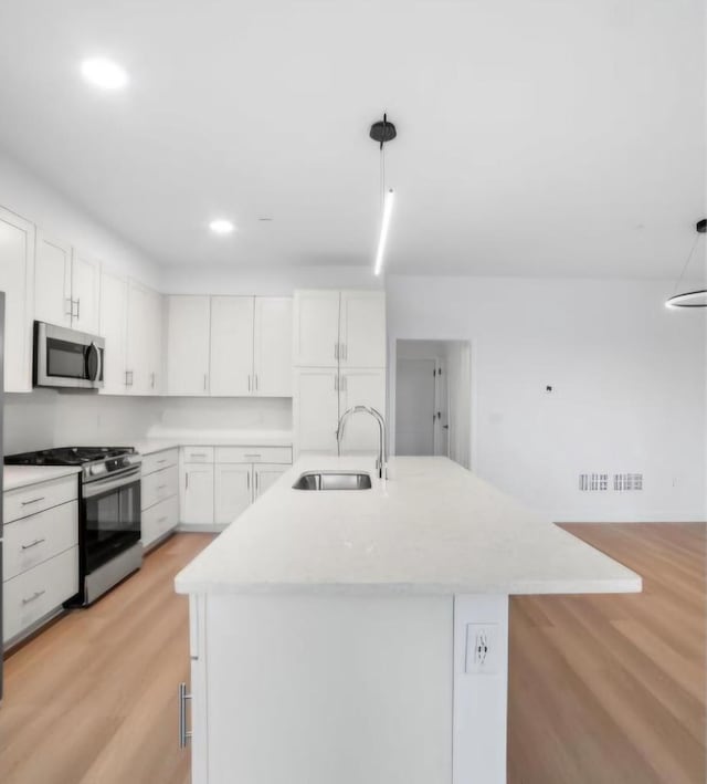 kitchen with white cabinets, appliances with stainless steel finishes, pendant lighting, and sink